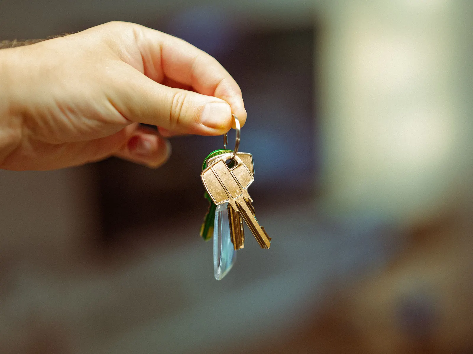 Hand holding a small bunch of brass house keys indoors