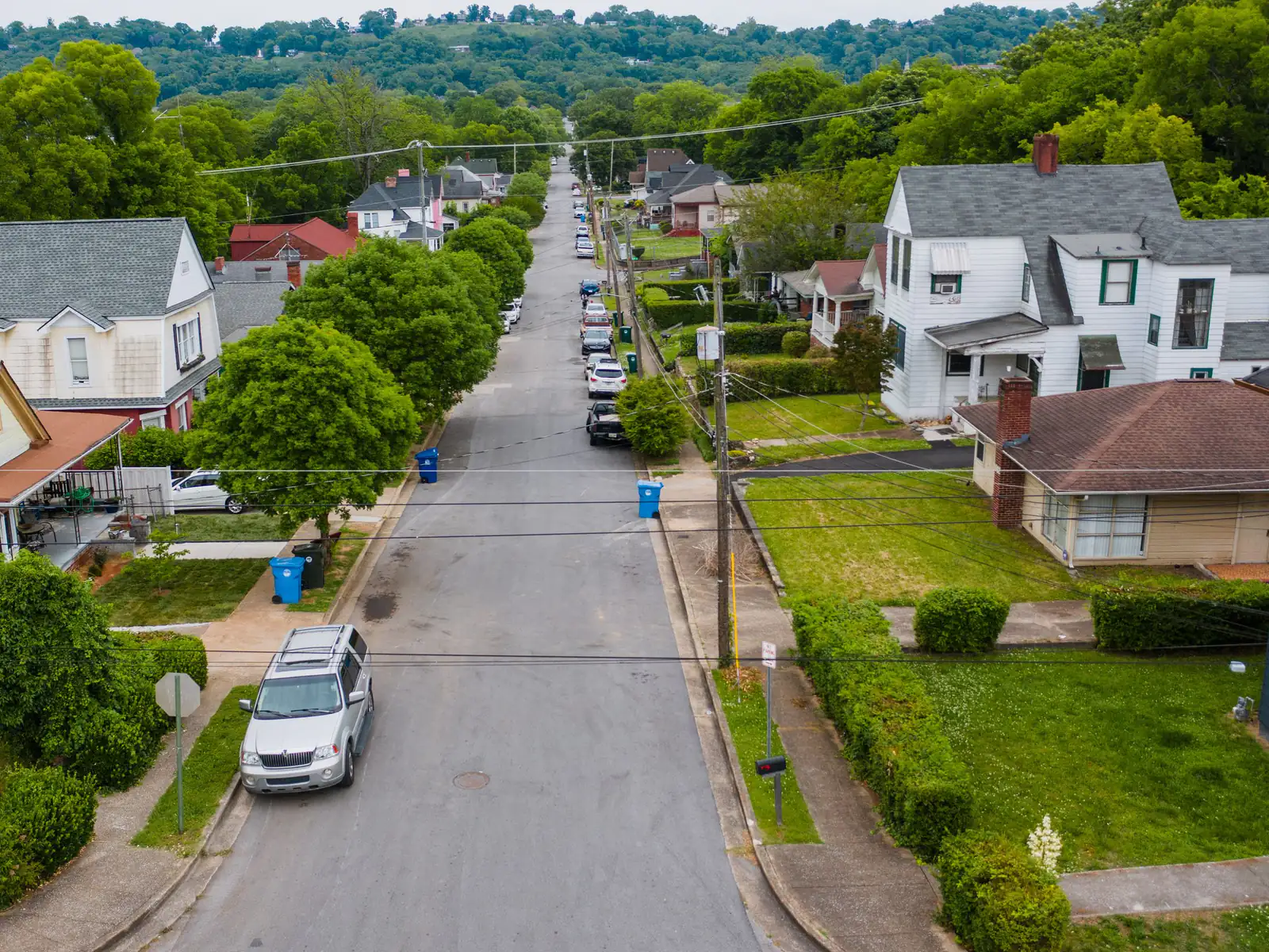 Elevated view down a straight neighbourhood street lined with houses and trees