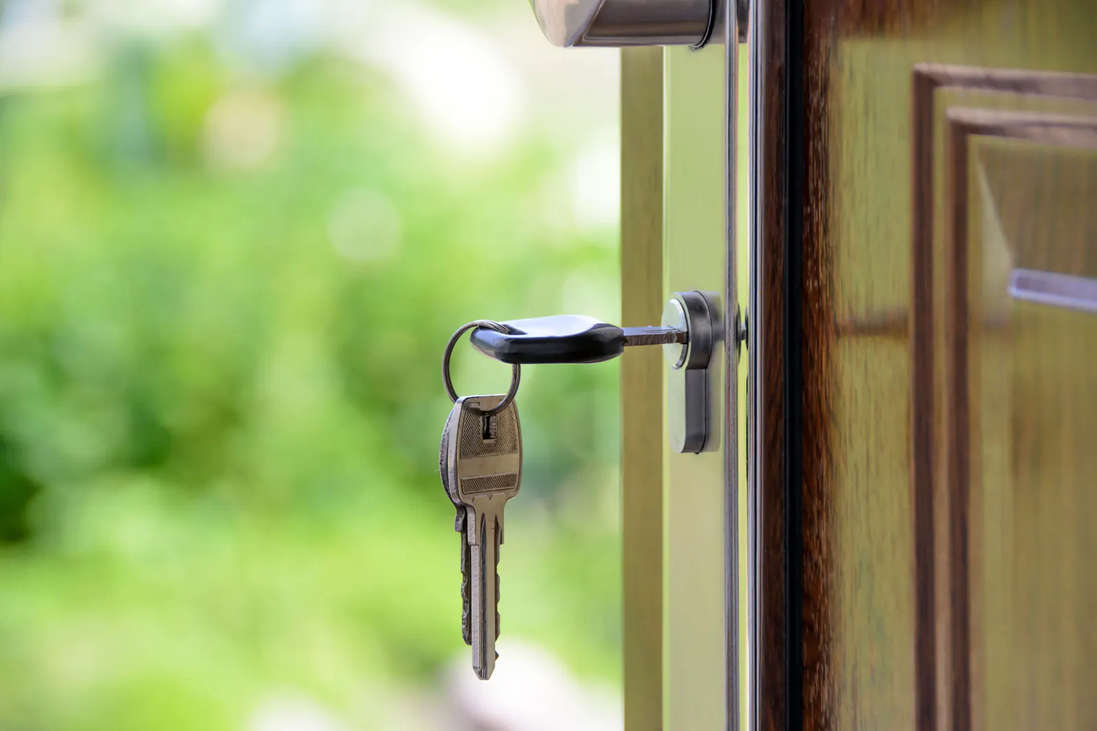 Bunch of keys hanging from the lock of an open wooden door