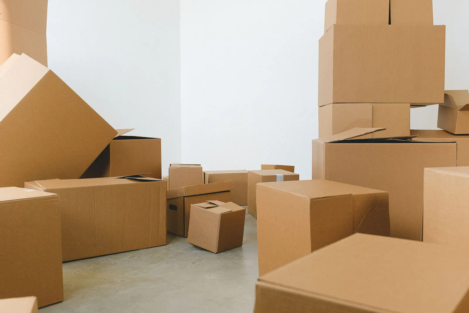 Cardboard moving boxes stacked across the floor of an empty white room