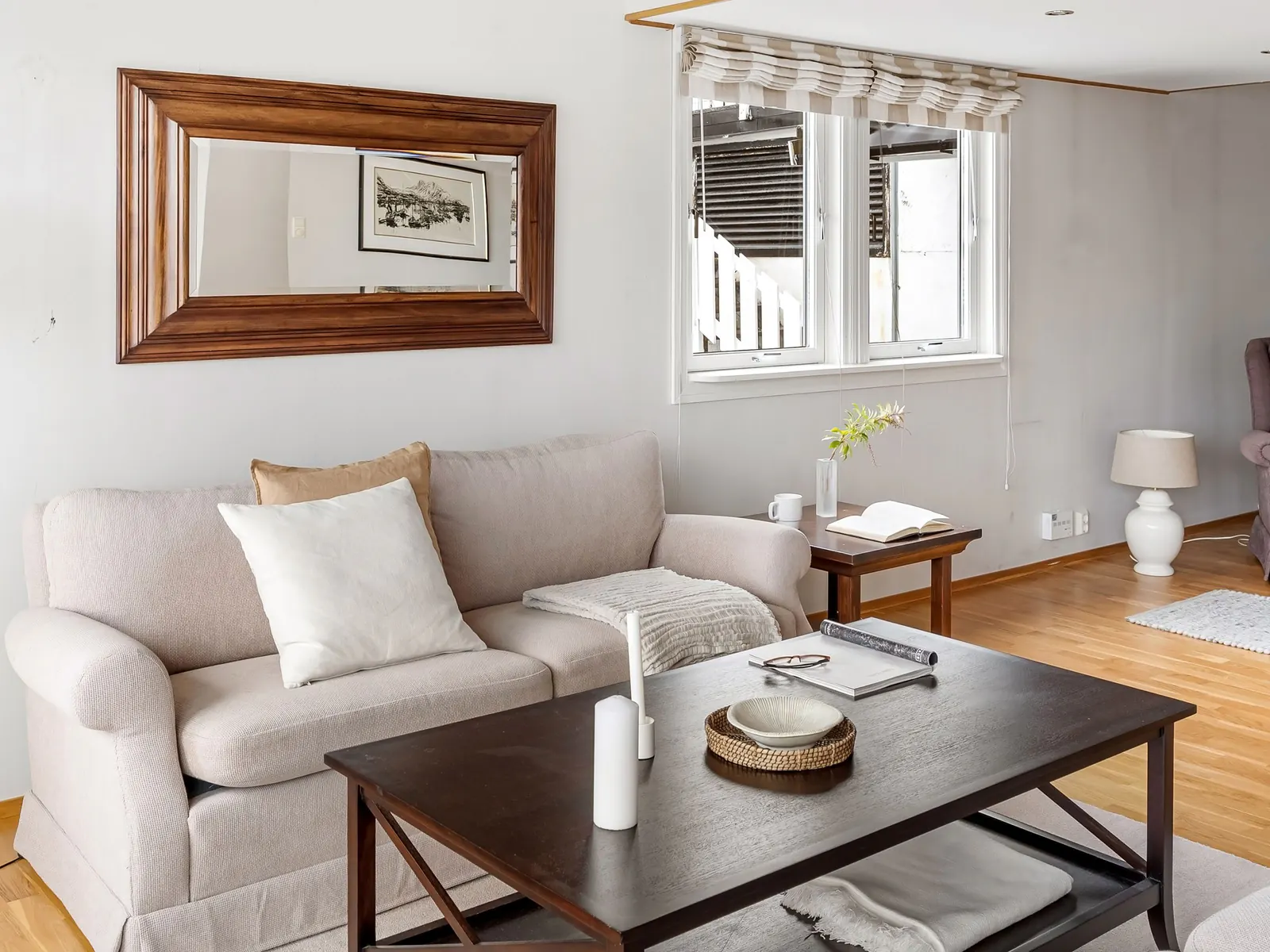 Living room with a grey sofa, dark coffee table and framed mirror