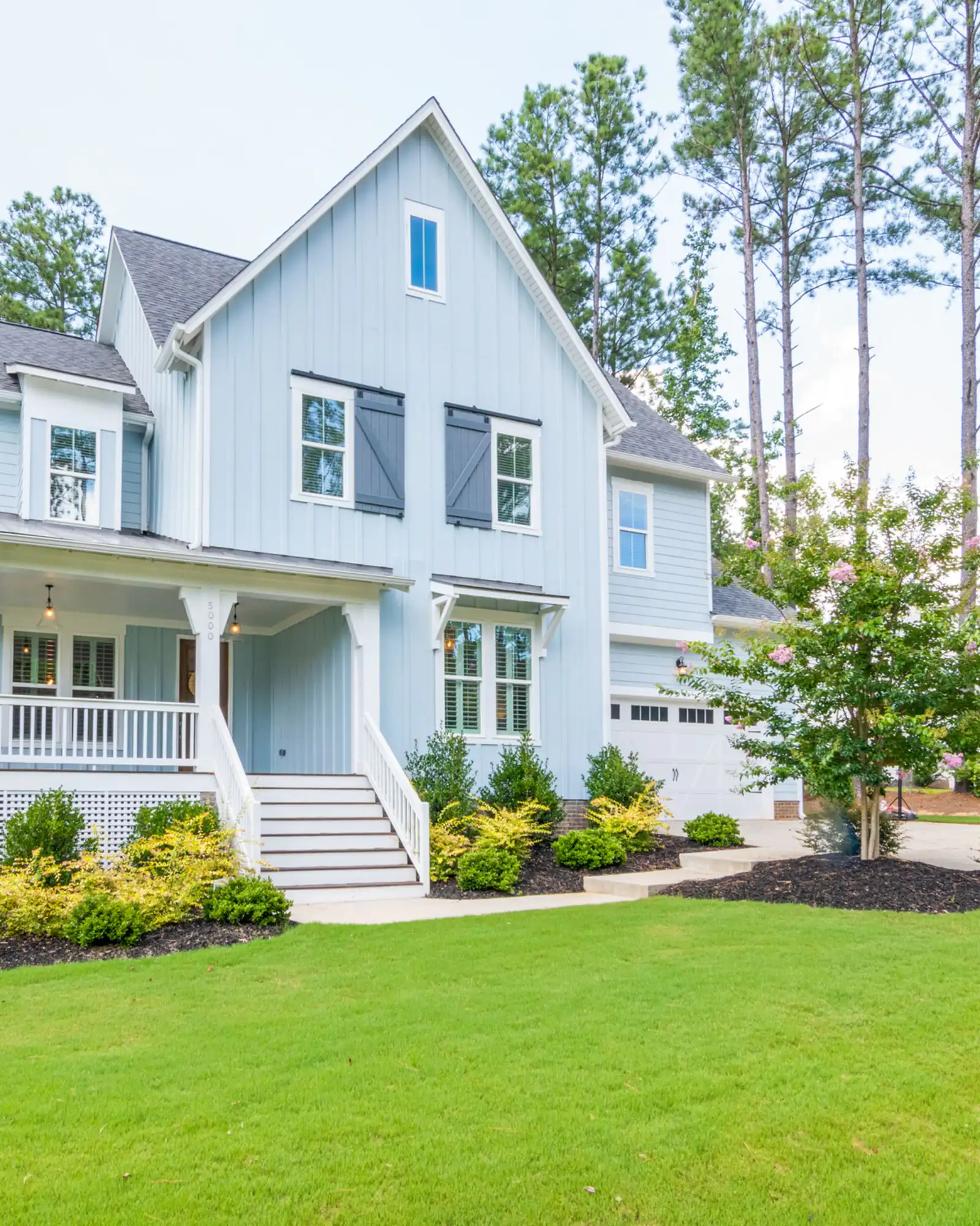 White two-storey house with a front porch on a green lawn