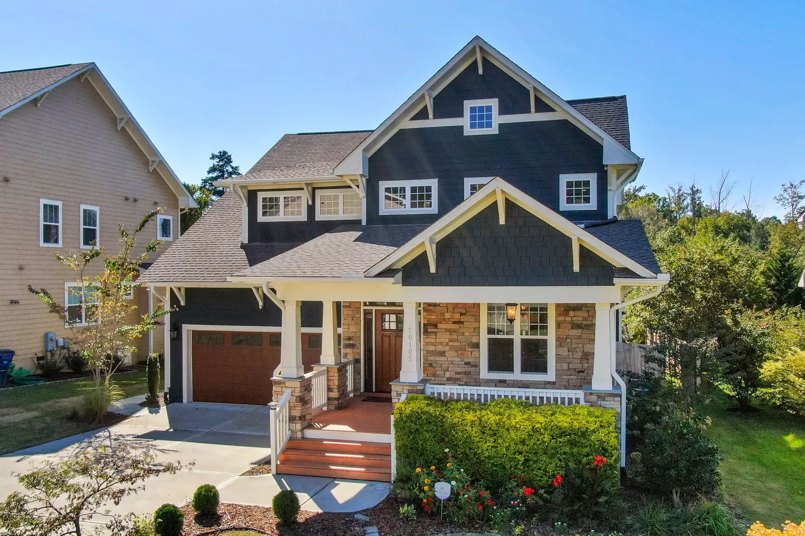Dark blue craftsman house with stone porch columns and red front steps