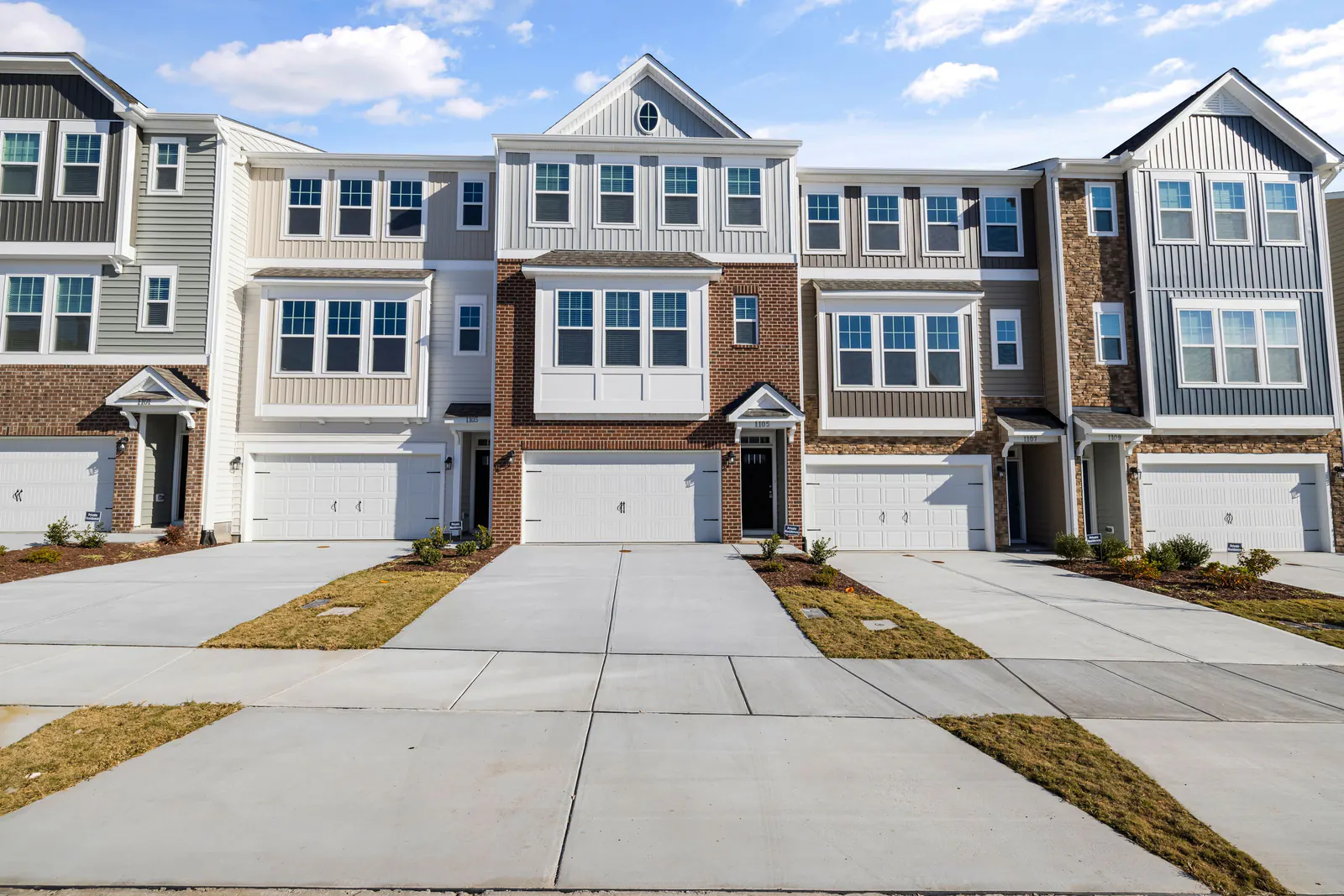 Row of three-storey townhomes with garages and concrete driveways