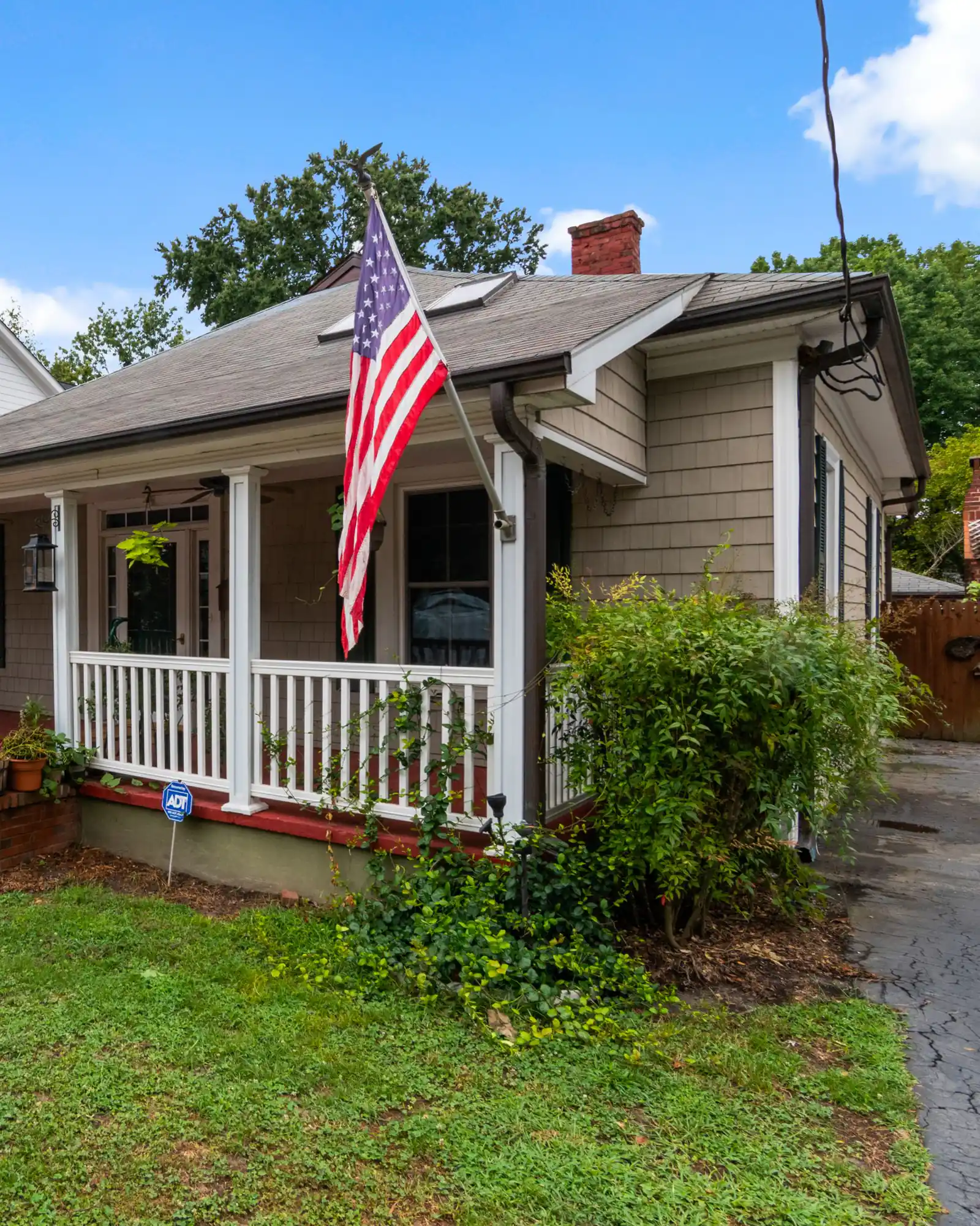 Bungalow with a covered porch, brick steps and a flag by the door