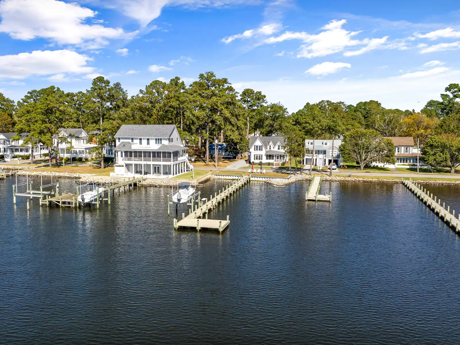 Waterfront homes with wooden boat docks on calm blue water under clouds