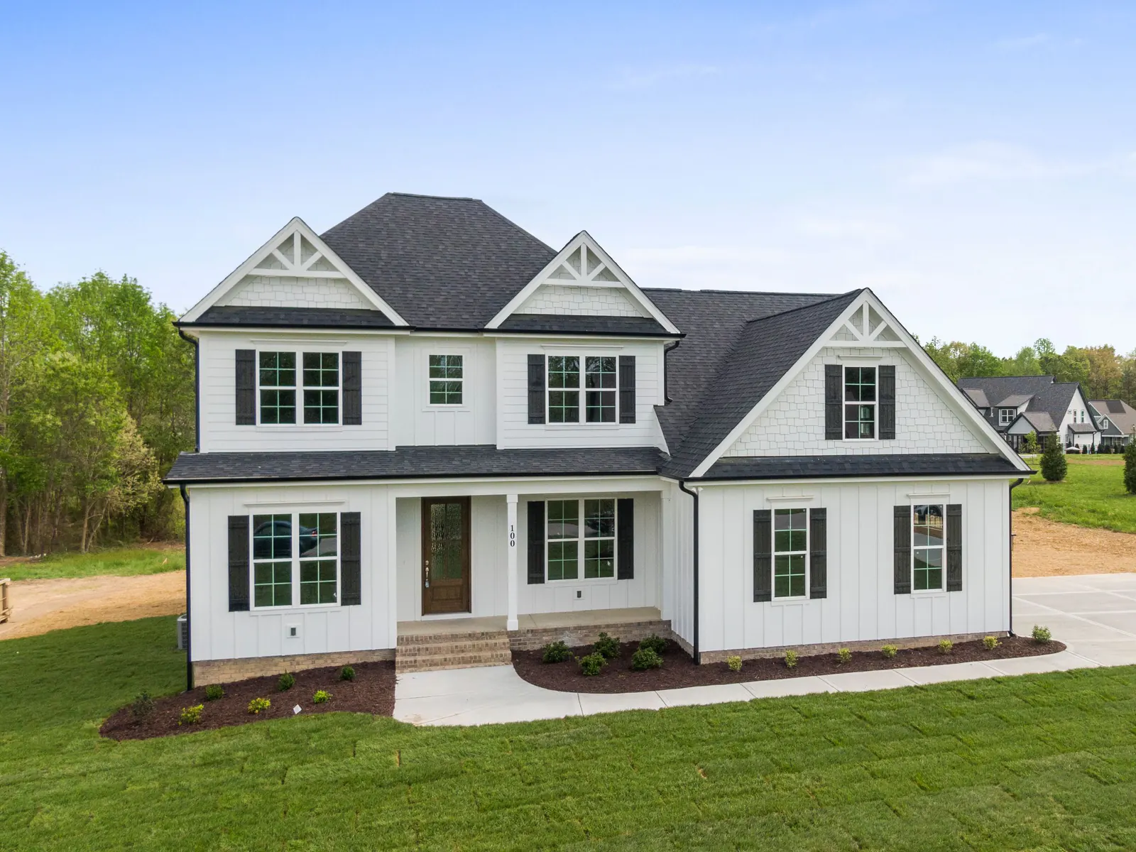 White two-storey house on a wide grassy lot at the edge of fields